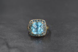 A 9ct gold blue topaz ring by QVC, the central cushion cut blue topaz within a halo surround of