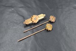 Two yellow metal pins having diamond chip set plaque terminals and a similar yellow metal bar brooch