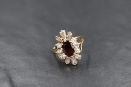 A 9ct gold paste set cluster ring, the central oval cut red paste in a twelve cubic zirconia