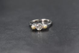 An 18ct white gold pearl and diamond set trilogy ring, the central old cut diamond measuring