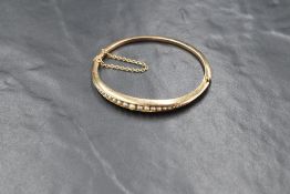 A Victorian yellow metal hinged bangle having 25 graduated split seed pearls (4 smallest missing) in