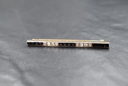 An Art Deco yellow metal diamond and onyx bar brooch having five alternate rows of four step cut