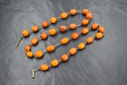 A butterscotch amber style bead necklace having oval beads measuring approximately 1cm, on a white