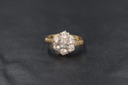 A 9ct gold floral cluster ring, having seven clear gemstones likely topaz with illusion shoulders,