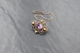 A yellow metal presumed gold amethyst and seed pearl set brooch, the central oval cut amethyst in