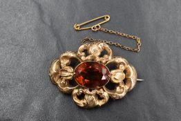 A Victorian yellow metal brooch having a central citrine style stone within a moulded open brooch