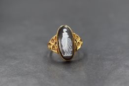 A yellow metal presumed gold agate cameo set ring, the oval cameo depicting a standing maiden in