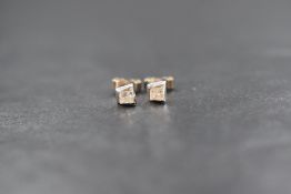 A pair of 18ct white gold diamond set stud earrings, the princess cut diamonds measuring