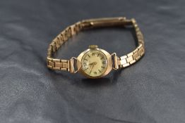A ladies vintage 9ct gold wrist watch by Perex having an Arabic numeral and baton dial to gold