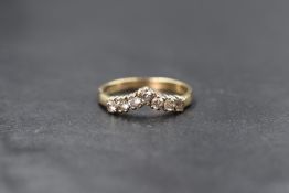 A 9ct gold cubic zirconia set wishbone ring, the seven round cut cubic zirconia in a wishbone