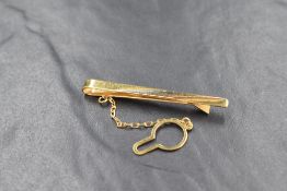 An 18ct gold tie slide with button safety chain, the slide having white and rose gold line