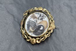 A large yellow metal mourning hair brooch, the central panel having decorative hair scrolls in an