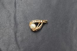 A small yellow metal pendant stamped 14K of teardrop form, having a cultured pearl with diamond chip