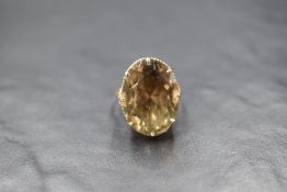 A yellow metal presumed gold smoky quartz set ring, the oval cut smoky quartz measuring