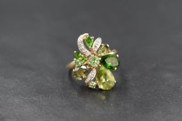A 9ct gold multi stone green open cluster ring having diamond chip set ribbon decoration on a 9ct