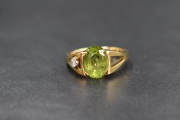 An 18ct gold peridot and diamond artisan style ring, the central oval peridot being set in a tension