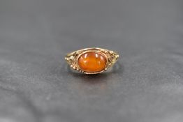 A 9ct gold amber set ring, the oval amber cabochon in a bezel setting, having decorative pierced