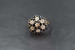 A 9ct gold sapphire and diamond chip cluster ring, the central diamond chip in a six sapphire