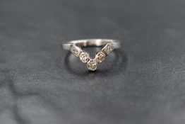 A platinum and diamond wishbone ring having three brilliant cut circular diamonds and two princess