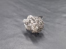A white metal multi cluster stylised diamond ring stamped 750, the central raised diamond being
