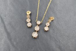 A 14ct gold and diamond necklace with matching earrings, the necklace having a graduated trio of