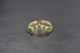 An 18ct gold emerald and diamond wishbone ring, the five marquise cut emeralds, total approx 0.