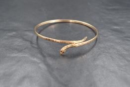 A yellow metal presumed gold snake cuff bangle, the bangle having textured decoration with a snake