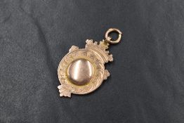 A 9ct rose gold medallion, of circular form having a scroll engraved border, crowned with a coronet,