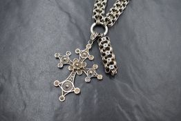 A Victorian white metal celestial link book chain necklace having a later filligree cross pendant,