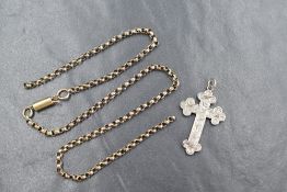 A white metal hollow cross pendant having engraved scroll decoration with a broken yellow metal