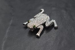 A white metal diamond encrusted articulated frog brooch stamped 750, the frog having approx 120 pave