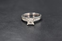 A platinum princess cut diamond solitaire ring having a 1ct princess cut diamond in a raised 4