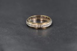 A 9ct gold clear gemstone likely topaz or sapphire set full eternity band, the round cut gemstones