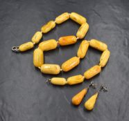 An egg yolk amber bead necklace having graduated cylindrical beads, on a white knotted cord, on a