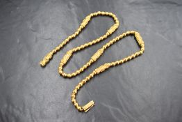 A 22ct and 18ct gold beaded necklace, the 18ct gold chain being covered by 22ct gold circular