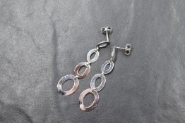 A pair of white metal presumed gold drop earrings, the articulated drops of four graduated pierced