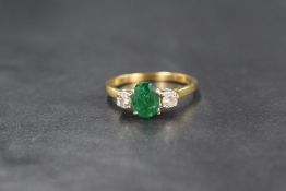 An 18ct gold emerald and diamond set three stone ring, the central oval cut emerald measuring