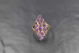 A 9ct gold amethyst set plaque ring, the central round cut amethyst in a twelve round cut amethyst