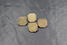 A pair of 9ct gold cufflinks of octagonal form having engine turned decoration and chain connectors,