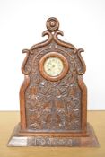 An early 20th-century Ansonia-style oak carved mantel clock, with a decorative top finial, relief