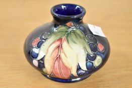 An early 20th-century Moorcroft pottery 'Leaf and Grape' pattern vase, featuring distinctive tube-