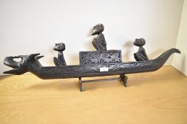 A large 20th-century presumed Indonesian Folk Art dark wood boat, featuring a zoomorphic canoe-