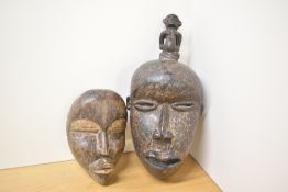 Two African hand-carved wooden tribal masks, presumed Ivory Coast examples, featuring expressive