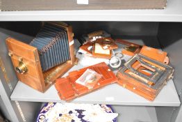 A folding mahogany field camera with an asortment of back plates and spare parts
