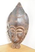 A 19th-century Ivory Coast wooden Baoule portrait mask, of elongated form, fine detailed features
