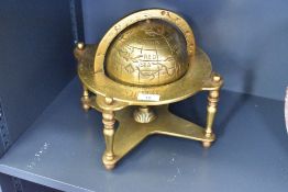 A 20th-century brass astrological world globe, mounted on a stand featuring zodiac signs and all
