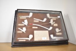 A large framed traditional clay pipe display, featuring ten replicas of a selection of historical