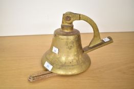 A late 19th to early 20th-century Nautical brass bell, mounted to a hinged wall bracket with a