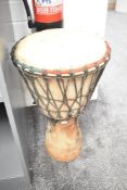 A 20th-century African carved hardwood Djembe, featuring an animal-skin covered goblet, a rope