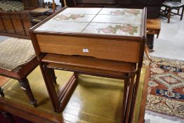 A vintage teak nest of three tables, the top table having frieze drawer and foliate tile top,